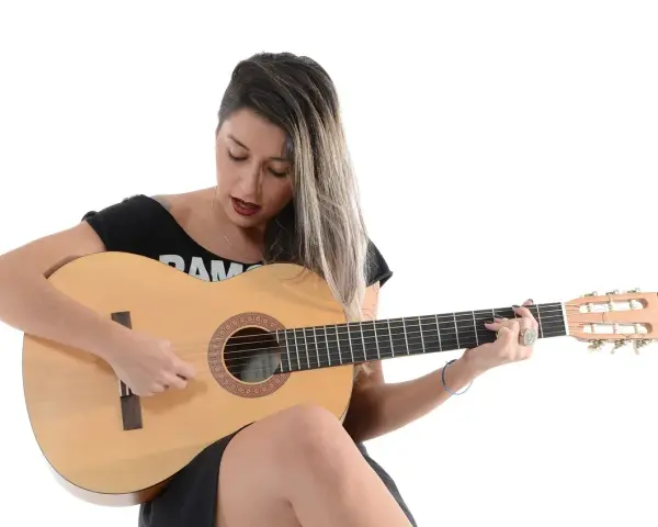 Kobieta gra na gitarze, nucąc stare piosenki country.