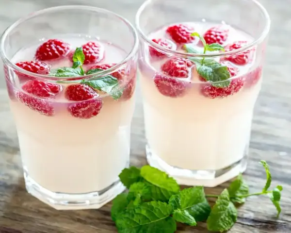 Dwa orzeźwiające drinki z malinami i miętą, idealne na letnie popołudnie. Wyglądają jak pyszne bacardi malinowe.