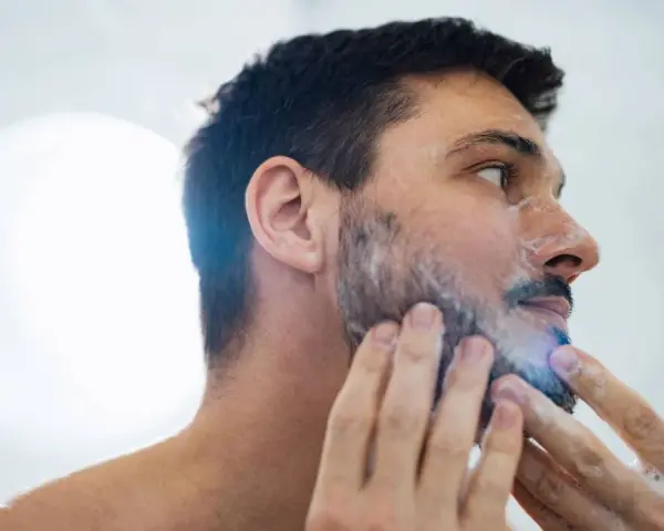 Hombre aplicándose espuma para quitarse la barba.
