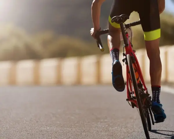 Cyclist in neon-accented shorts and polka-dot socks powering up a hill, embodying a dedicated sprint workout plan.