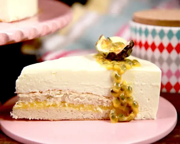 En bit tårta med len vit chokladmousse, passionsfruktssås och en halv passionsfrukt som dekoration.
