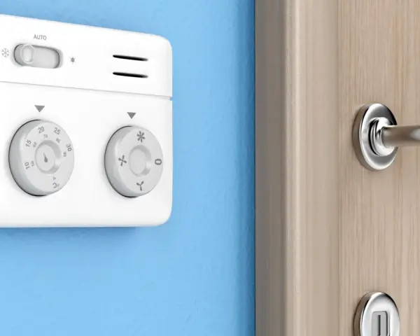 Termostato bianco su muro blu, parte di sistemi termoregolazione evoluti per un comfort ottimale. Manopole per impostare la temperatura.