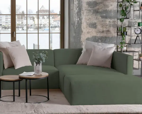 Divani verdi in colori di tendenza, con cuscini chiari e tavolini rotondi. Un angolo relax moderno con vista sul lago.