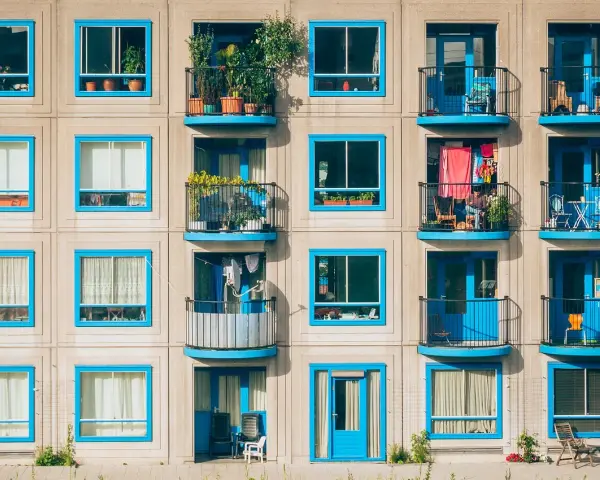 Elegancka loggia i balkon z niebieskimi ramami okiennymi na betonowej fasadzie budynku.