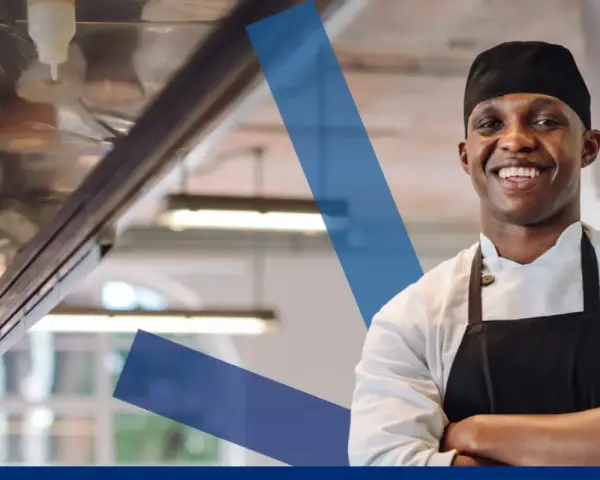 Chef sonriente con delantal negro, listo para servir. Conoce los derechos y obligaciones de un camarero.