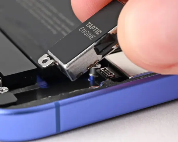 Dłoń wyjmuje moduł Taptic Engine z wnętrza telefonu, element odpowiedzialny za zaawansowane wibracje i 3D Touch.