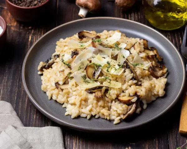 Kremowe risotto z pieczarkami, posypane parmezanem i ziołami.