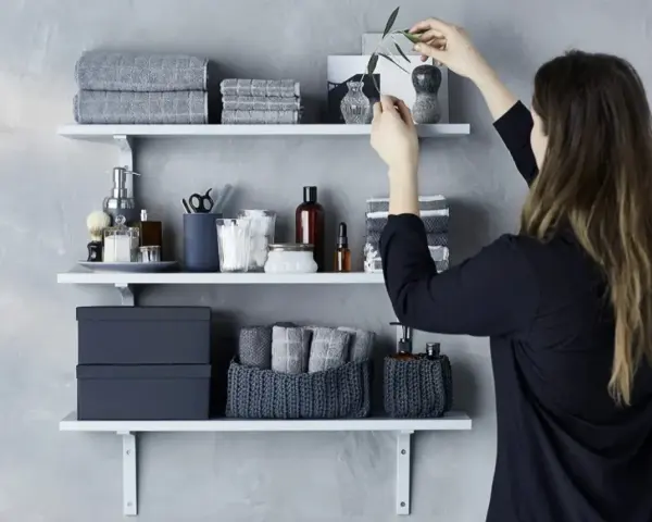 Idee mensole ingresso: organizzazione bagno con asciugamani grigi, scatole e cestini in maglia.