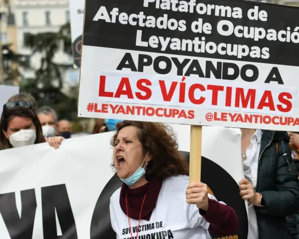 Manifestantes protestan contra la ocupación de vivienda habitual. Una mujer grita, portando un cartel que apoya a las víctimas de #Leyantiocupas.