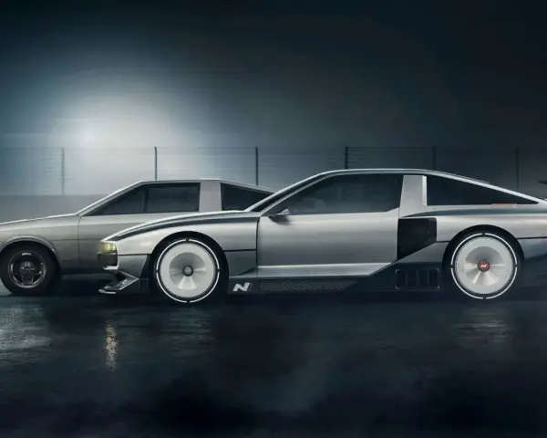 Dwa samochody Hyundai N Vision 74 stoją obok siebie na mokrej nawierzchni. Jeden jest bardziej klasyczny, drugi futurystyczny.