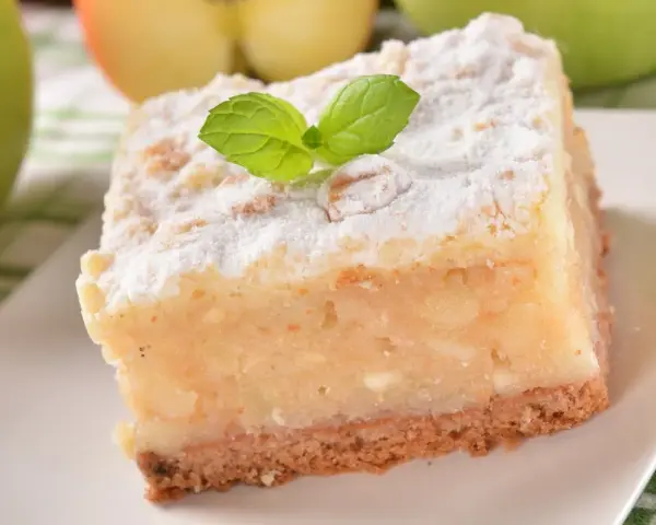Pyszne, ekspresowe ciasto z jabłkami, posypane cukrem pudrem i udekorowane listkiem mięty. Idealne na szybki deser.