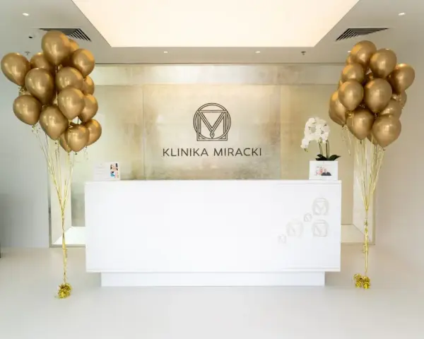 Recepcja kliniki z bukietami złotych balonów i rzeźbą.