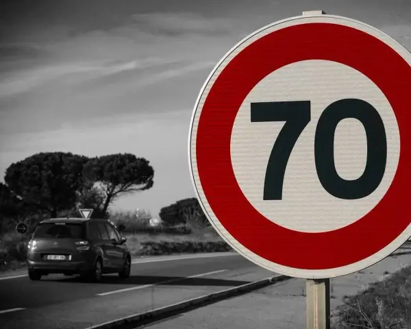 Znak drogowy ograniczający prędkość do 70 km/h, samochód na drodze.