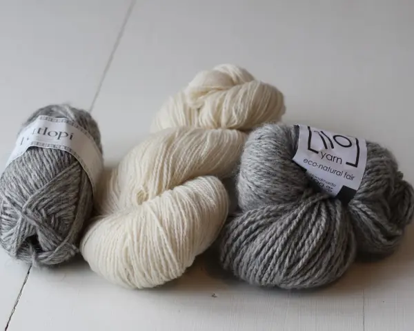 Mjuka garnnystan i grått och naturvitt. Perfekt ullgarn som inte kliar, redo att bli ditt nästa stickprojekt.