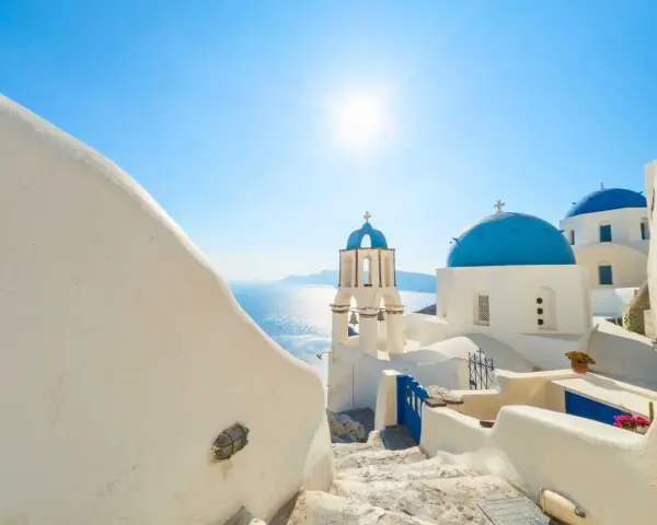 Santorini, październik. Słoneczna pogoda, białe domy i niebieskie kopuły kościołów nad Morzem Egejskim.