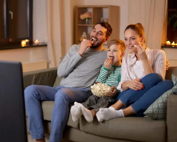 Rodzina zajada popcorn podczas oglądania filmów familijnych.