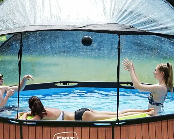 Trois personnes jouent dans une piscine hors sol sous un abri transparent. Idéal pour savoir comment fabriquer un abri piscine hors sol.