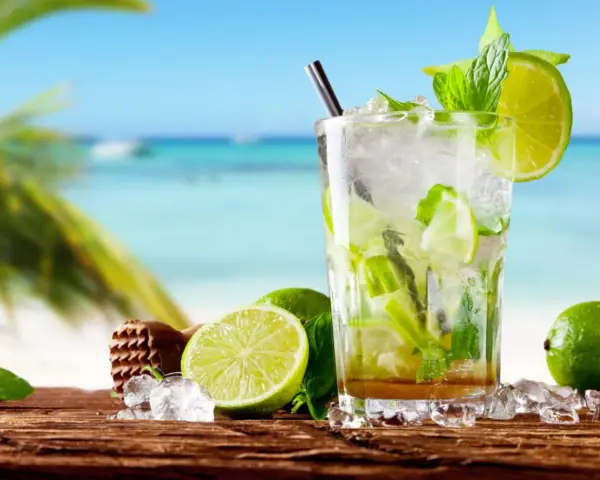Orzeźwiające drinki z miętą i limonką na tle plaży. Idealne na upalne dni.