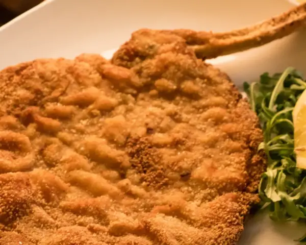 Cotolette al forno dorate e croccanti, servite con rucola fresca e una fetta di limone.
