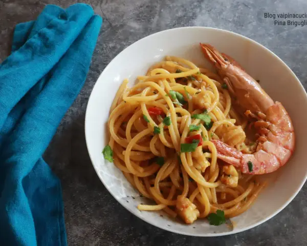 Spaghetti con gamberoni surgelati, un piatto gustoso e veloce. Un gamberone intero adorna la pasta condita con pomodorini e prezzemolo.
