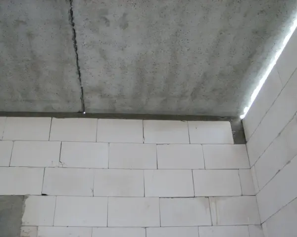 Betonowy strop z widocznym pęknięciem nad ścianą z białych pustaków.