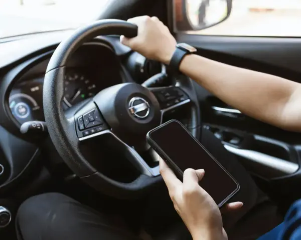 Fahrer hält Handy in der Hand, während er fährt. Hoffentlich wird er nicht geblitzt mit Handy in der Hand!