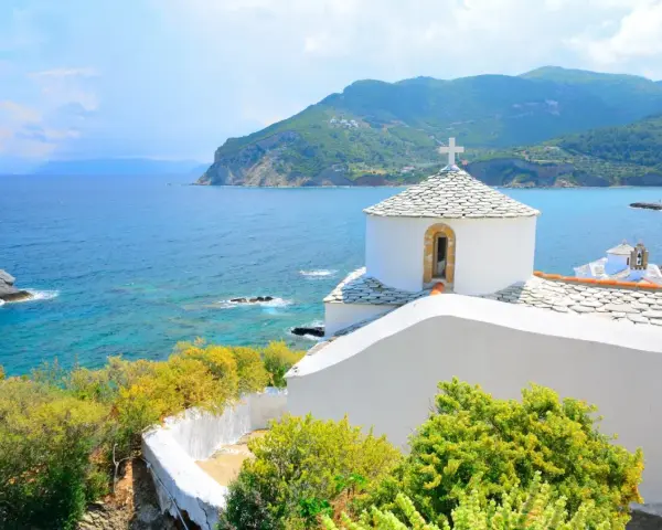 Malownicza zatoka i białe kościółki na wzgórzu. Idealne miejsce na skopelos wakacje.