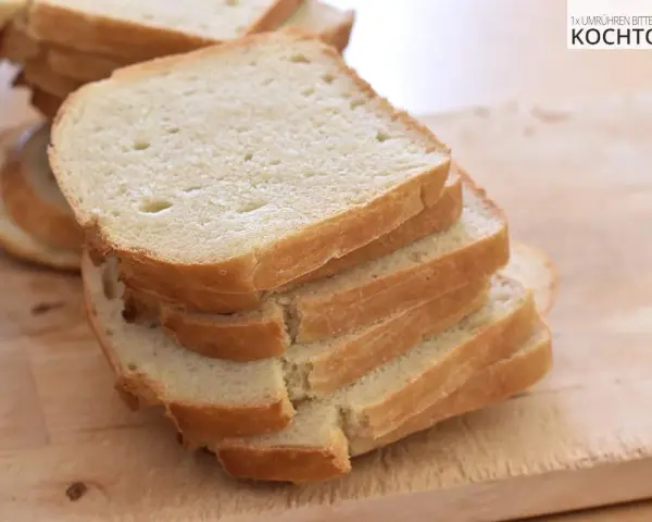 Gestapelte Scheiben eines hellen Sandwichbrots auf einem Holzbrett. Perfekt für ein einfaches Sandwich brot rezept.