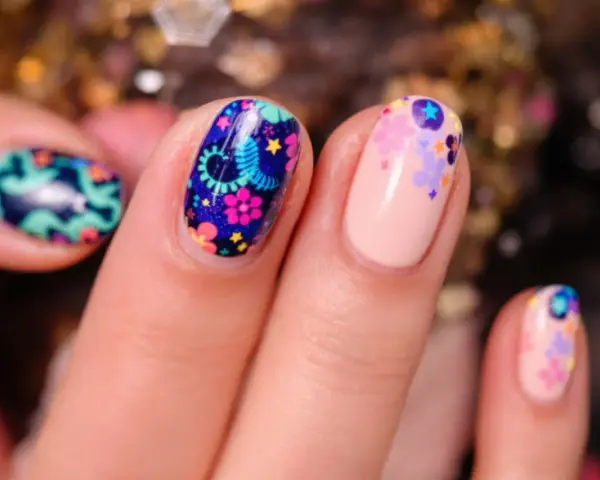 Comment avoir de beaux ongles : des ongles décorés de motifs floraux colorés et de petites étoiles sur fond bleu nuit ou nude.