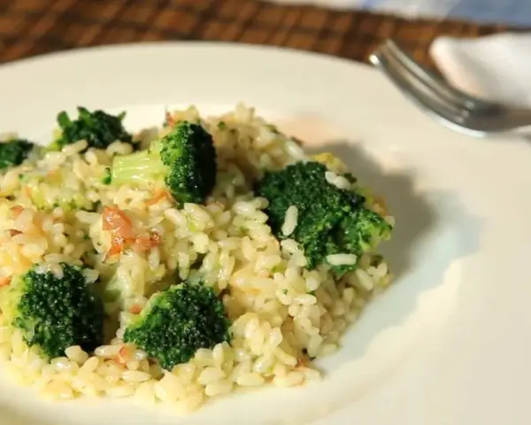 Delicioso arroz con brócoli cremoso, servido en un plato blanco con un tenedor al lado.