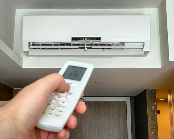 Mano ajustando el control remoto del aire acondicionado a 20 grados, ideal para saber a cuanto poner el aire acondicionado en verano y refrescar el hogar.