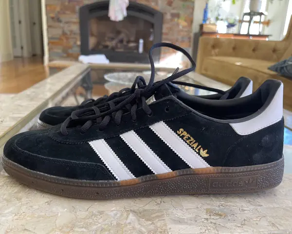 Czarne buty Adidas Spezial z białymi paskami i złotym napisem. Zwróć uwagę na detale, jak rozpoznać oryginalne buty Adidas.