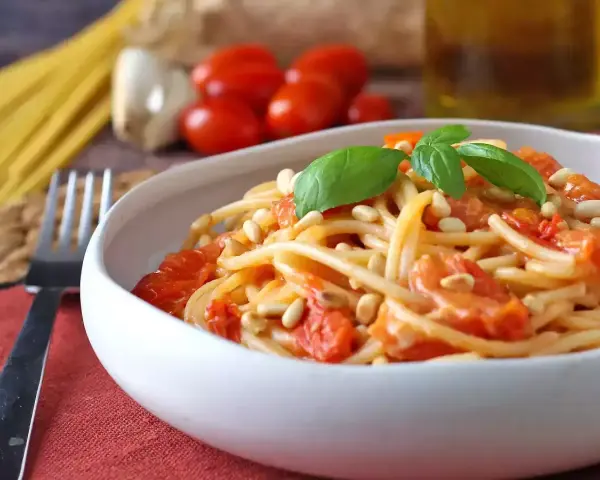 Spaghetti con pomodorini, pinoli e basilico, un'idea per sughi estivi per pasta freschi e veloci.