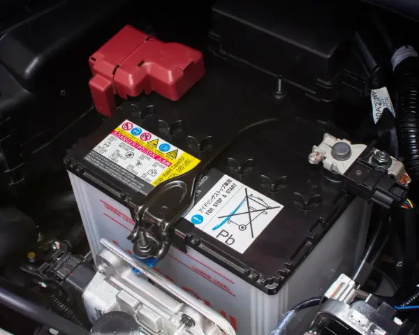 Autobatterie im Motorraum, mit Warnhinweisen. Die Batterie ist tiefentladen und muss ersetzt werden.