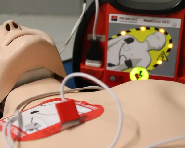 Manekin do resuscytacji z podłączonym defibrylatorem AED.