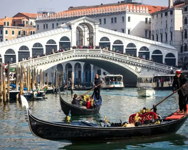 La gondola veneziana scivola sull'acqua, con il Ponte di Rialto sullo sfondo, un'icona di Venezia.