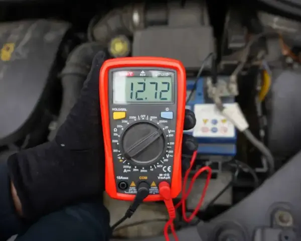 Multimetr pokazuje 12.72V, co może oznaczać, że akumulator nie trzyma napięcia. Sprawdzanie stanu baterii w samochodzie.