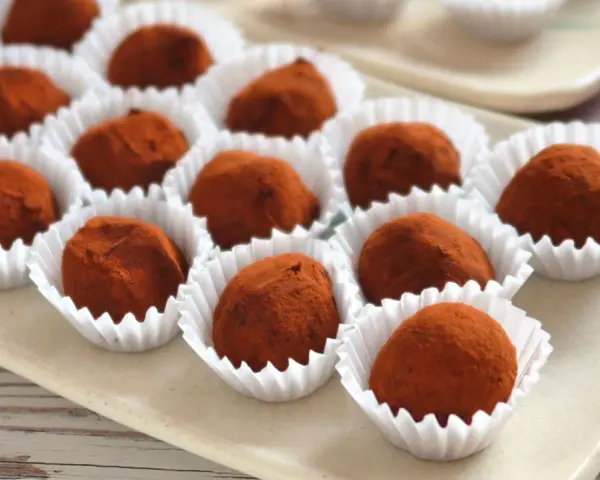 Deliciosas trufas de chocolate cubiertas de cacao, presentadas en sus envoltorios blancos.