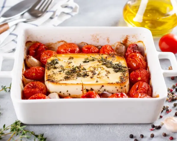 Pieczeni ser feta z pomidorkami koktajlowymi i czosnkiem, idealne dania na imprezę na ciepło.