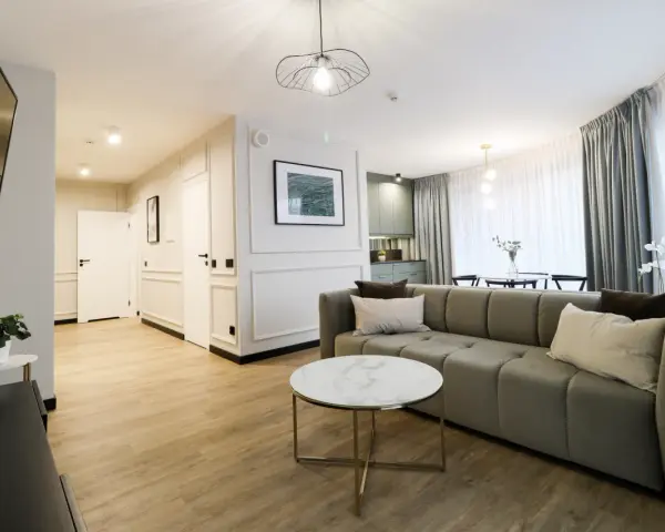 Nowoczesny apartament suite, z wygodną kanapą, stolikiem kawowym i widokiem na kuchnię.