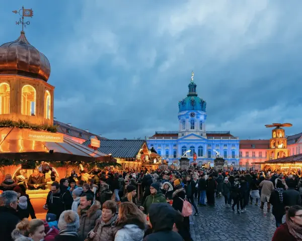 Besucher genießen den Weihnachtsmarkt vor dem beleuchteten Schloss Charlottenburg in Berlin.