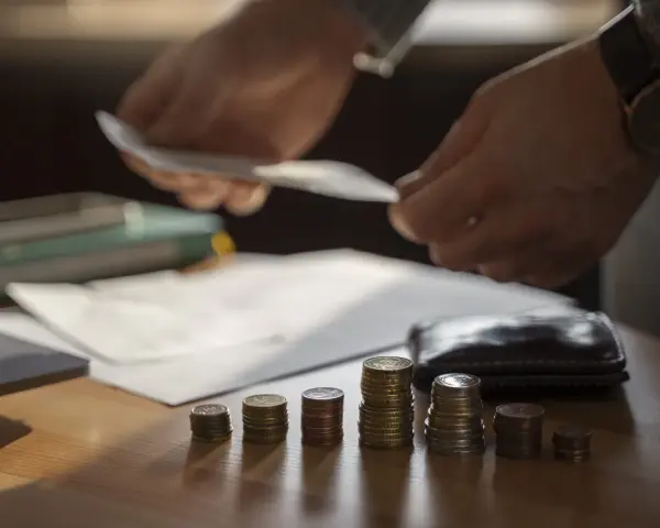 Ręce liczą pieniądze nad stosem monet, symbolizującym trudną sytuację finansową i potencjalną upadłość przedsiębiorcy.