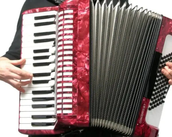 Ręce grają na czerwonym akordeonie, wydobywając dźwięki tego wspaniałego instrumentu.
