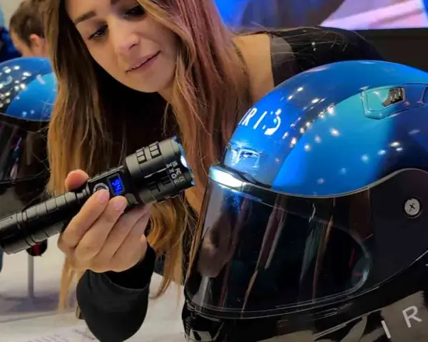Donna mostra un casco da moto blu con visiera, evidenziando la sua importanza per la sicurezza. È bene che il casco sia dotato di visiera.