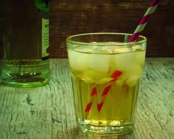 Orzeźwiający drink z lodem i słomką, idealny do przygotowania według przepisu na French Martini. Obok butelka alkoholu.
