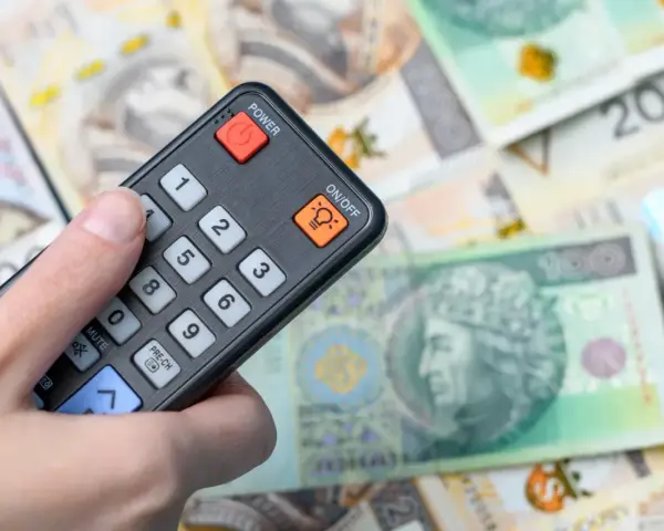 Pilot w dłoni, na tle polskich banknotów. Czy to symbol zwolnienia z abonamentu RTV i oszczędności?