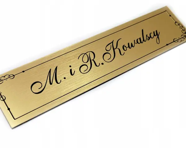 Elegancki, złoty szyld z napisem "M. i R. Kowalscy" w ozdobnej ramce.