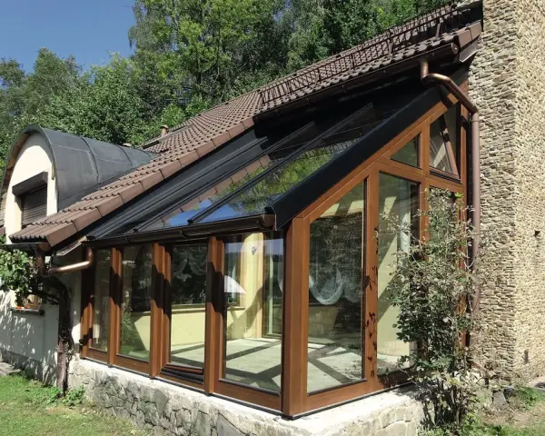 Nowoczesny ogród zimowy na tarasie, z drewnianymi ramami i przeszklonym dachem, idealny do relaksu przez cały rok.