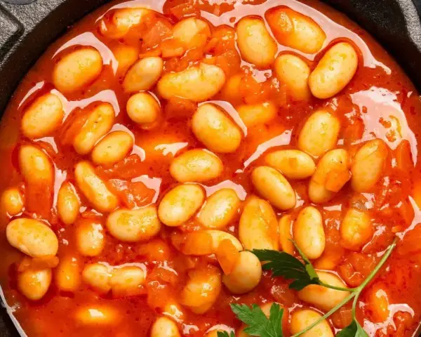 Pyszna fasolka po bretońsku przepis w garnku. Aromatyczne danie z białej fasoli w sosie pomidorowym, ozdobione natką pietruszki.