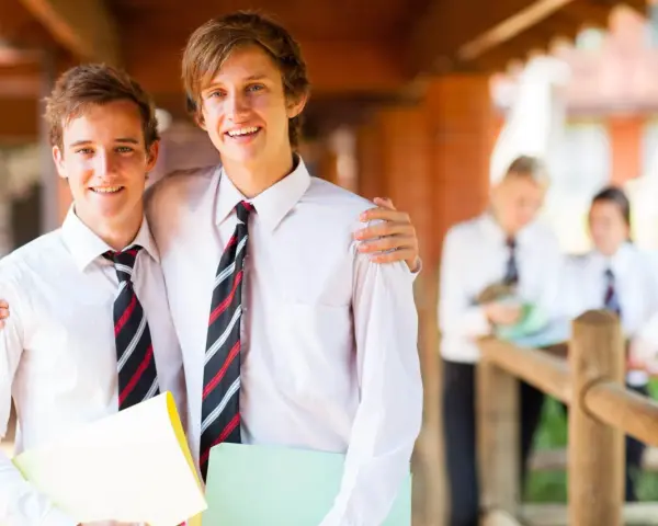 Deux adolescents souriants, portant des chemises blanches et des cravates, profitent de leurs vacances scolaires en Irlande.